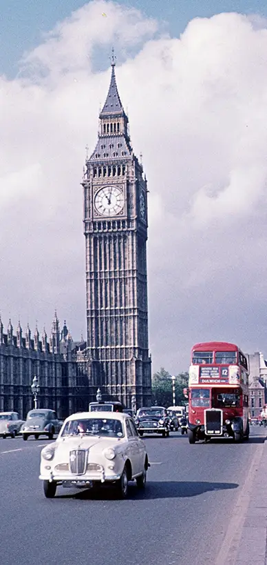 Big Ben and the Houses of Parliament with vintage cars and a red double-decker bus.
